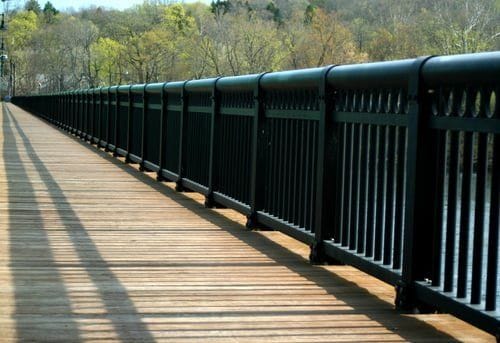 Long black powder-coated aluminum fence and railing along a waterfront walkway
