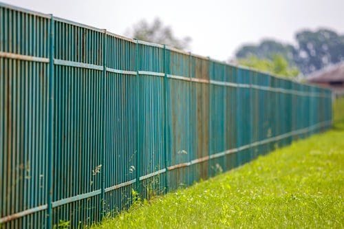 Green vinyl-coated chain link fence enclosing a property perimeter