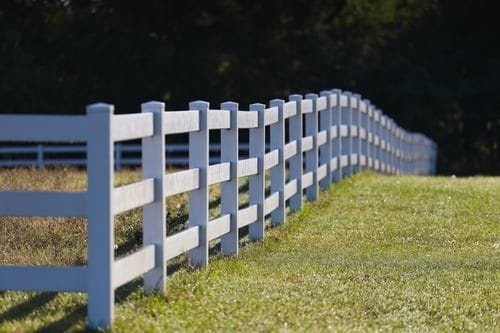White vinyl ranch rail fence running along a green Hampton Roads property line