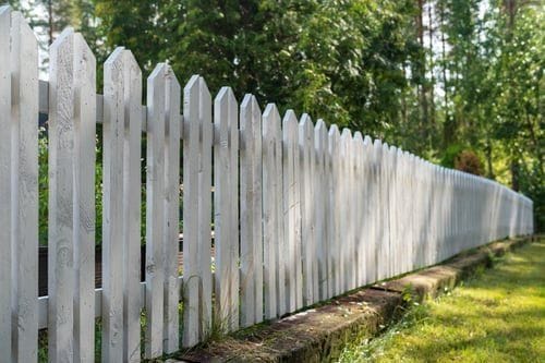 Long white picket fence line bordering a lawn in coastal Virginia