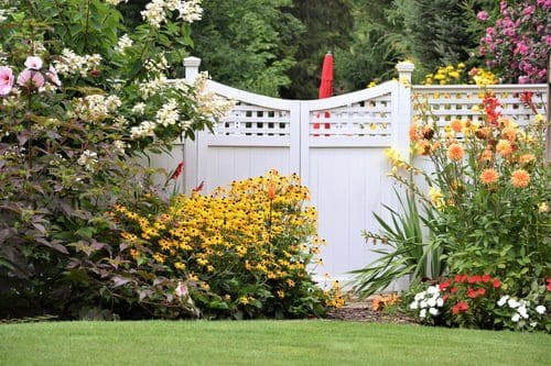Freshly installed white vinyl fence bordering a landscaped Hampton Roads yard